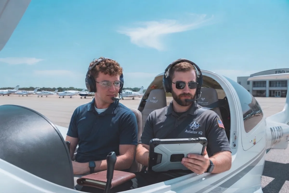 A flight instructor and student pilot reviewing notes on a tablet in the cockpit